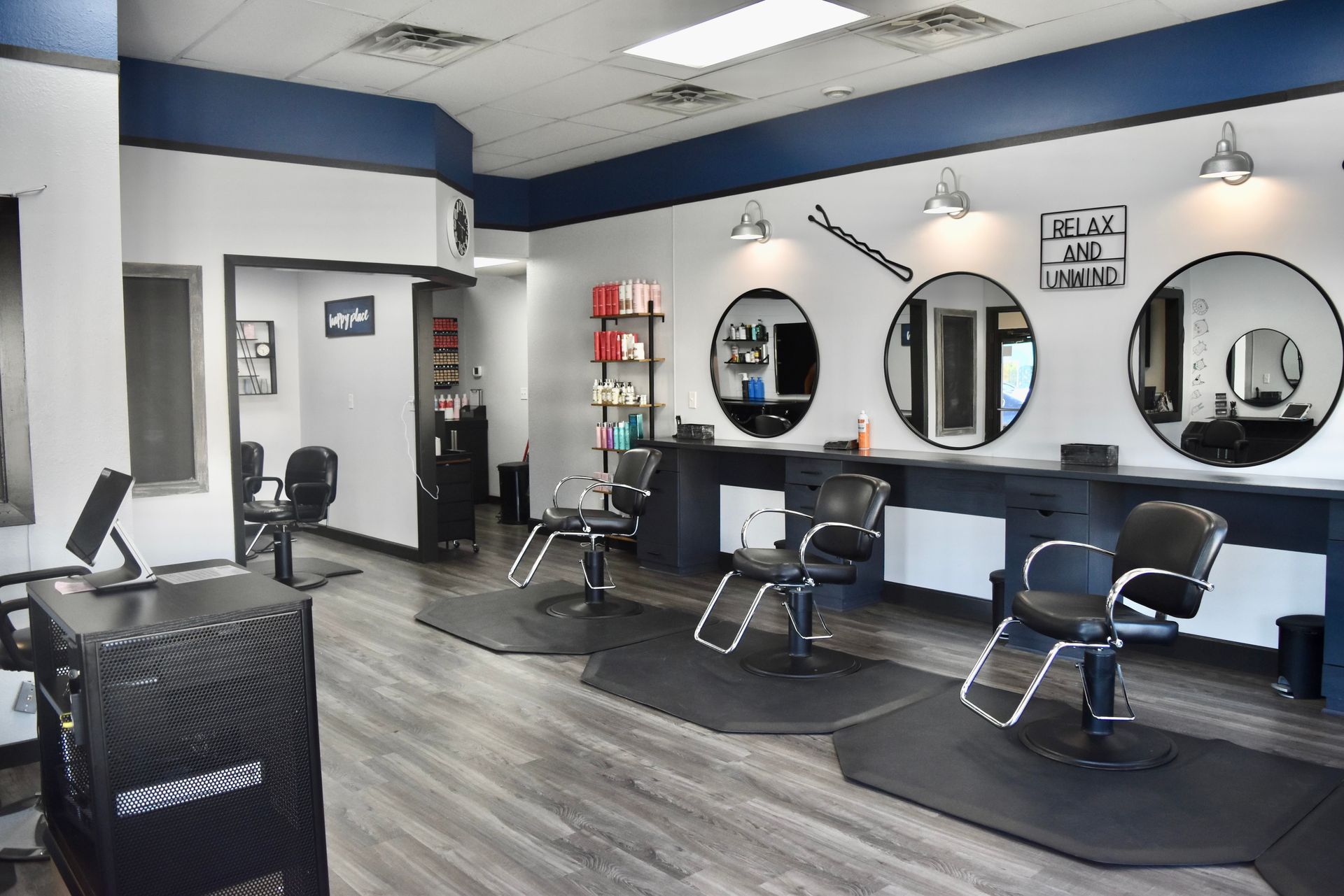 Hair salon interior with chairs, mirrors, and styling stations; blue and white color scheme.
