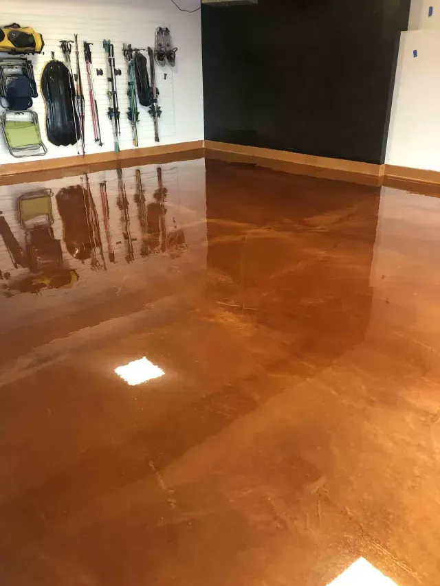 A glossy, metallic copper-colored epoxy floor in a garage with sports equipment mounted on the white wall.