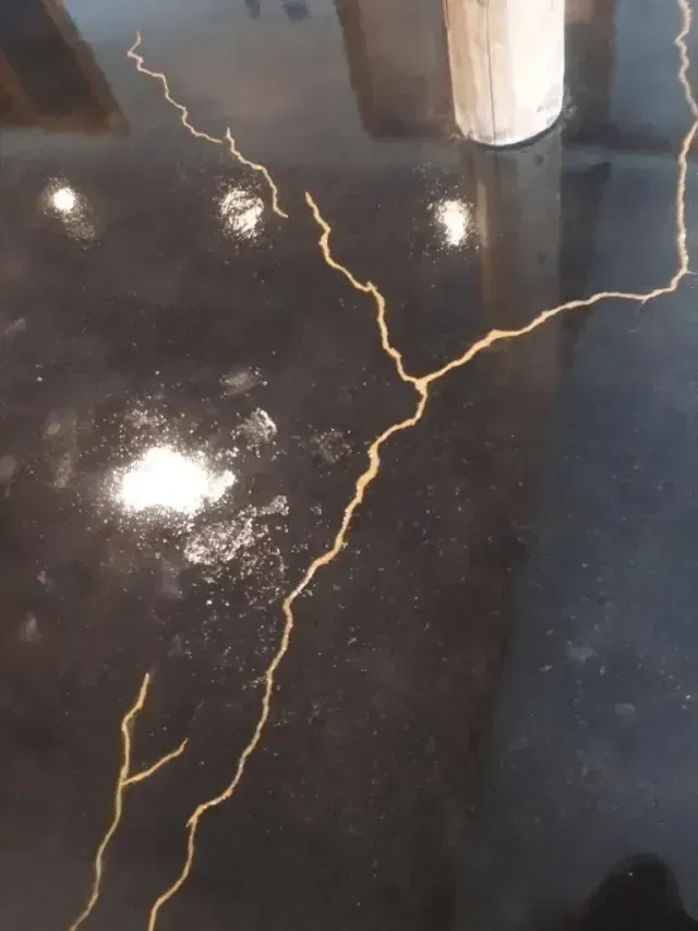 A glossy black floor features decorative, gold-filled cracks resembling branching lightning or river patterns.