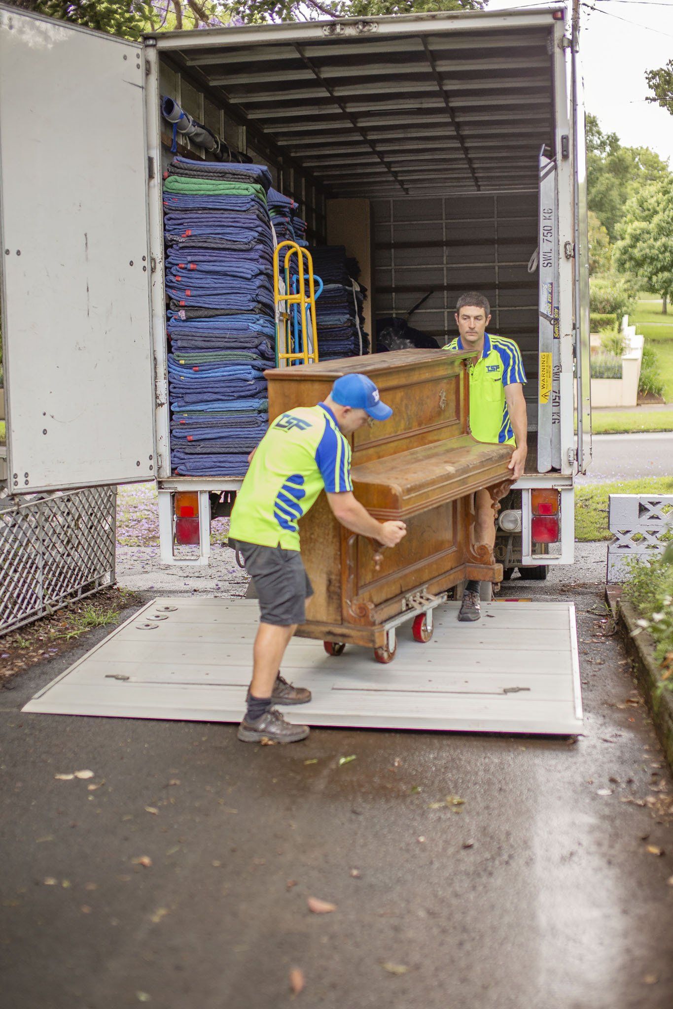 Sam and Lewis positioning an upright piano on the Toowoomba Sensitive Freight trucks taillift