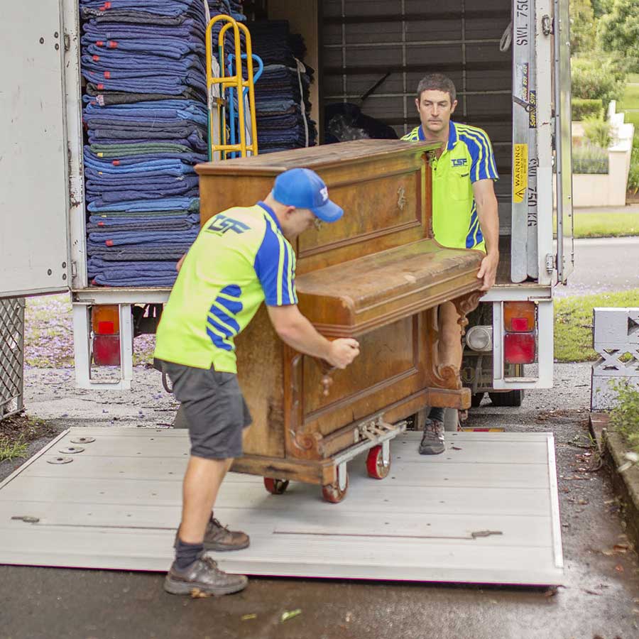 Lewis and Sam moving an upright piano into the back of the removal truck.