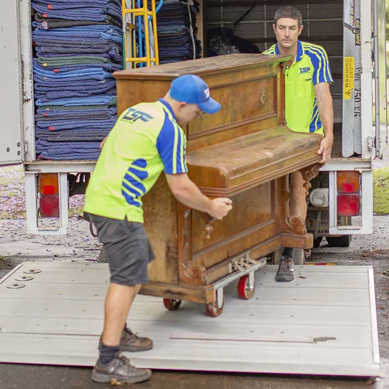 Lewis & Sam positioning an upright piano on the tail lift of the Toowoomba Sensitive Freight truck