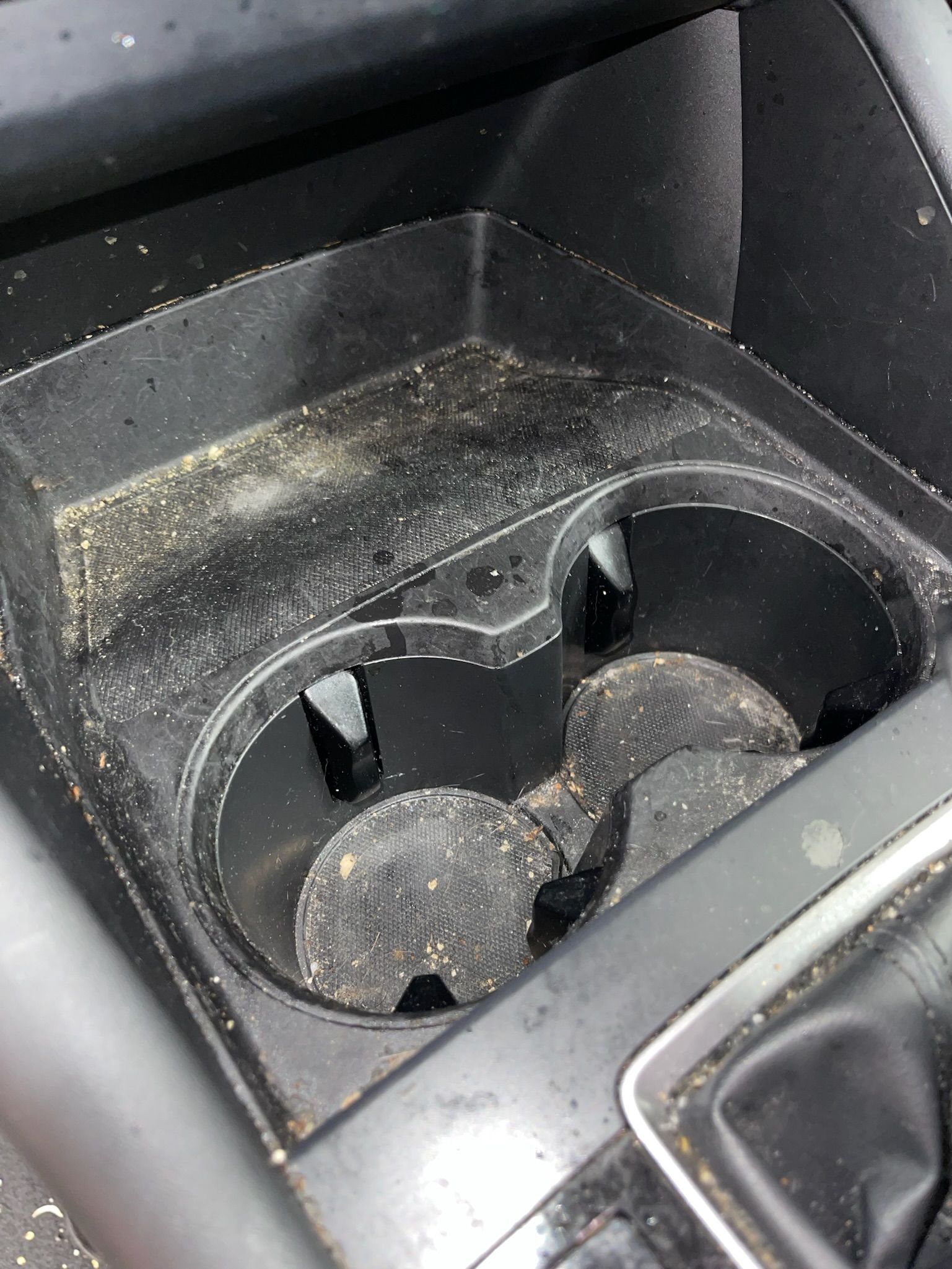 Dirty car cup holder with debris visible.