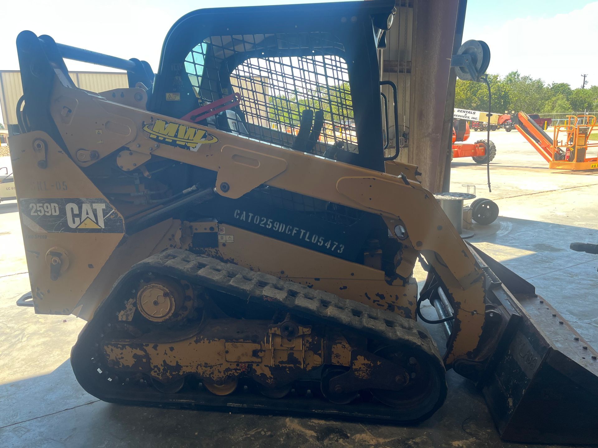 A yellow CAT 259D compact track loader with tracks, a bucket, and cab.