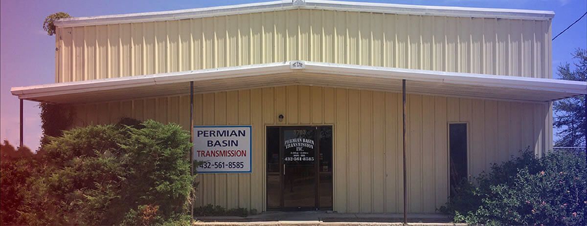 Small beige commercial building with a front door and a sign by the entrance.