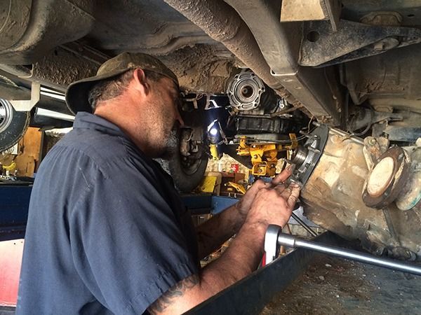 Mechanic inspecting vehicle undercarriage with a flashlight in a garage