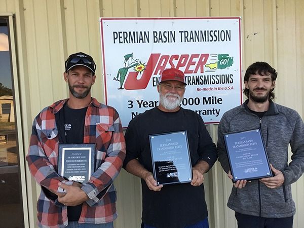 Three men holding plaques stand in front of a Permian Basin Transmission banner.
