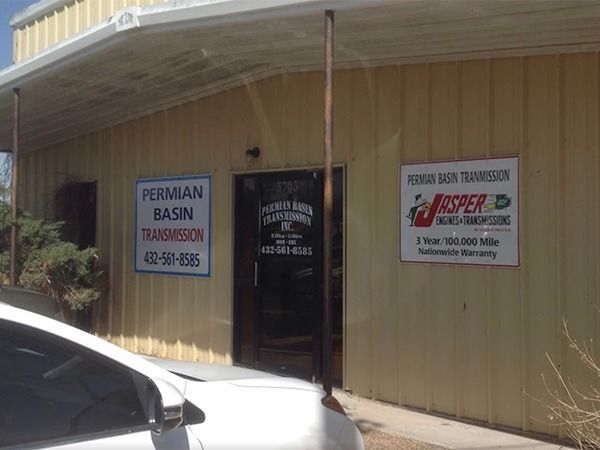 Storefront of a small business with signs and a parked car in front