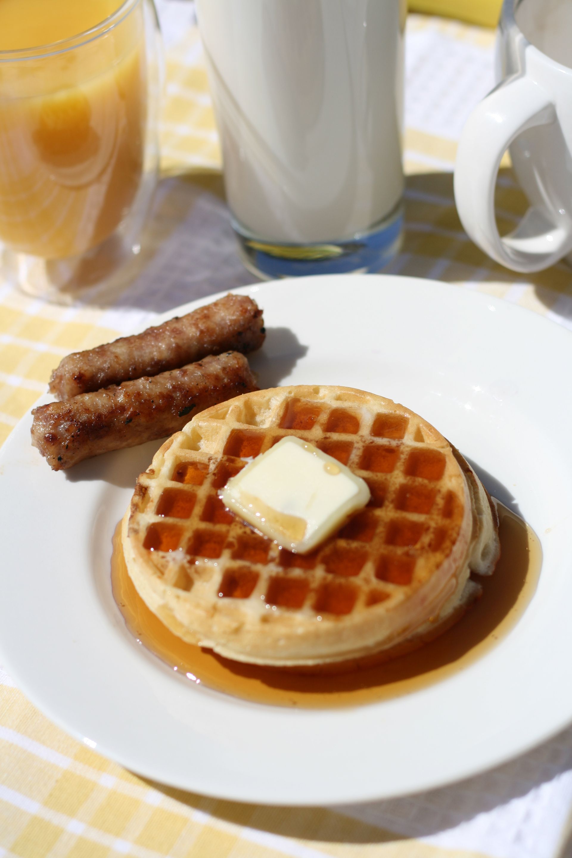 A waffle with butter and syrup on a white plate