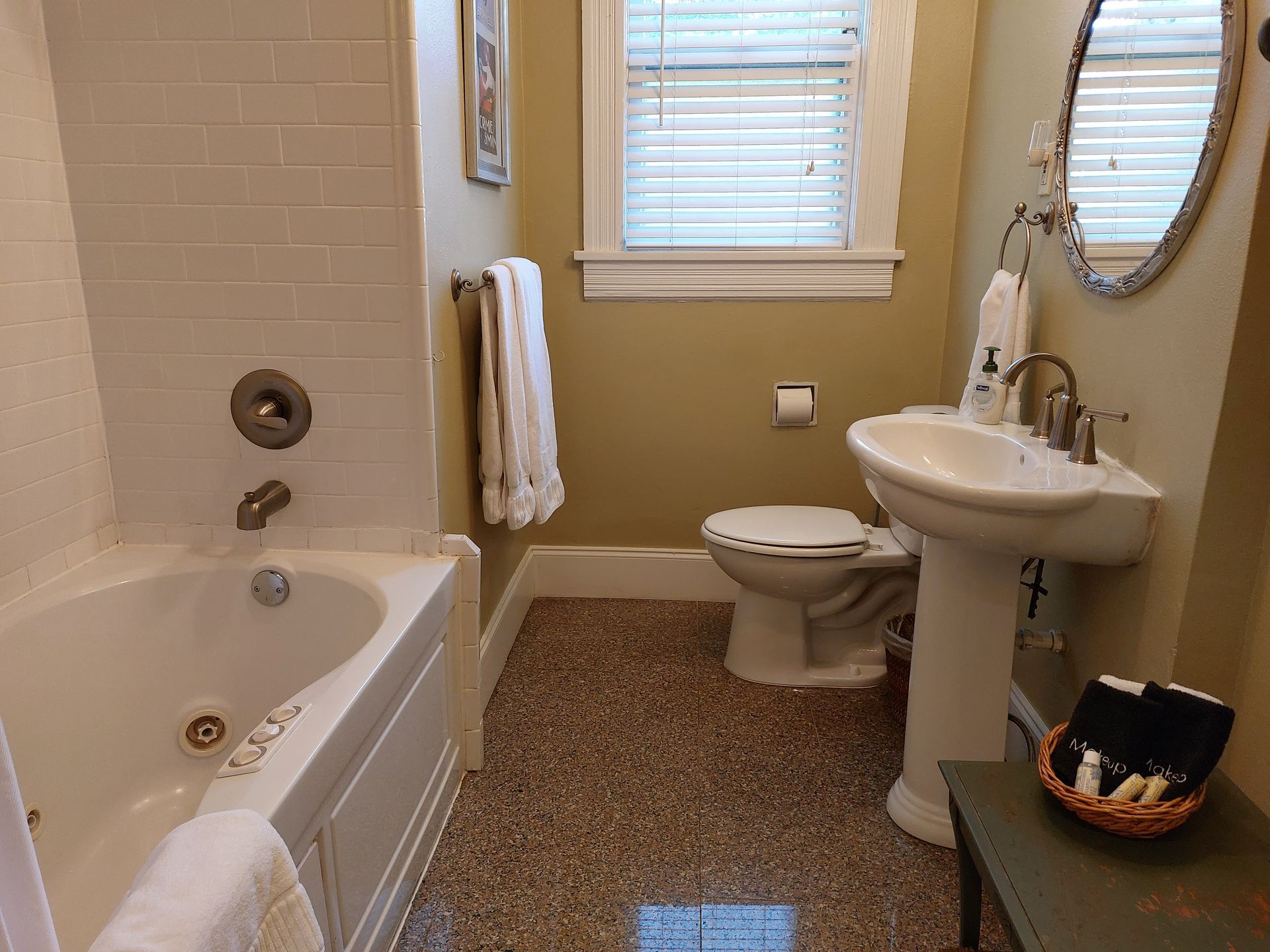 A bathroom with a tub , toilet , sink and mirror