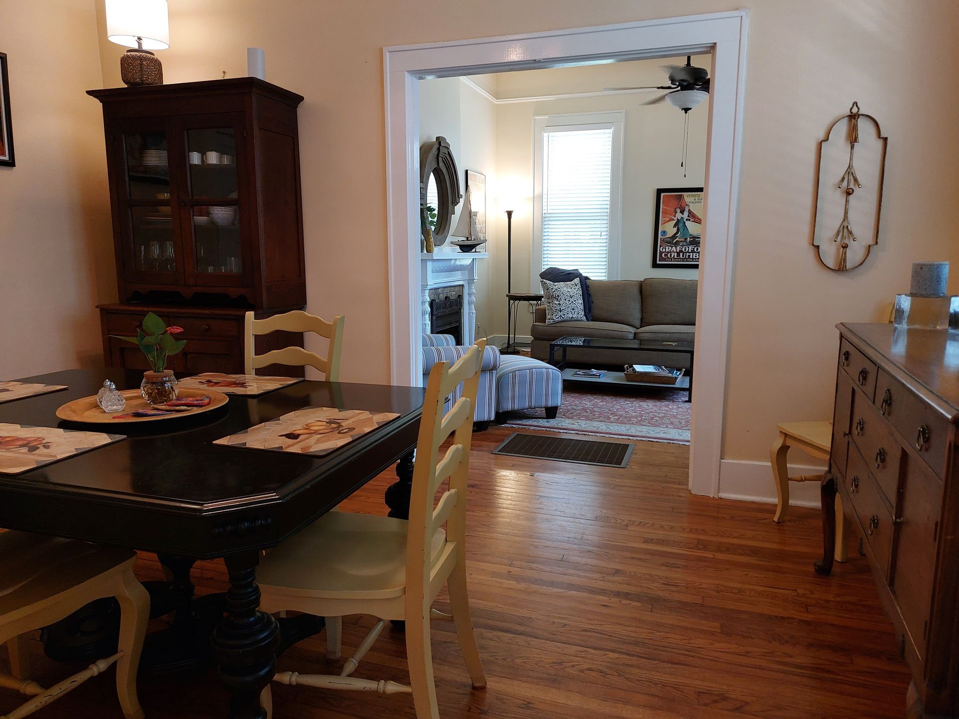 A dining room with a table and chairs looking into a living room