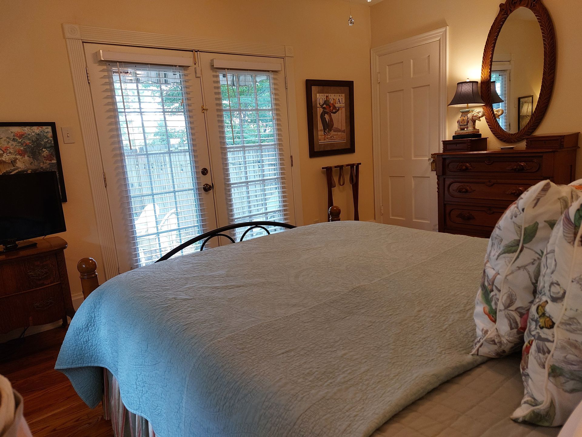 A bedroom with a bed , dresser , mirror and television
