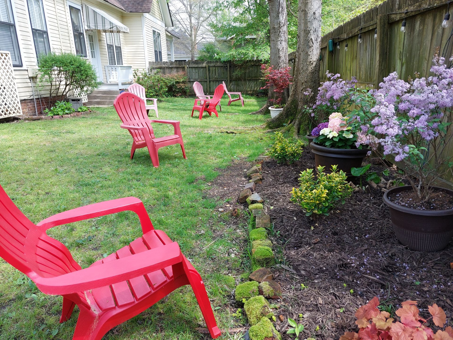 A lawn with red chairs and flowers in front of a house.