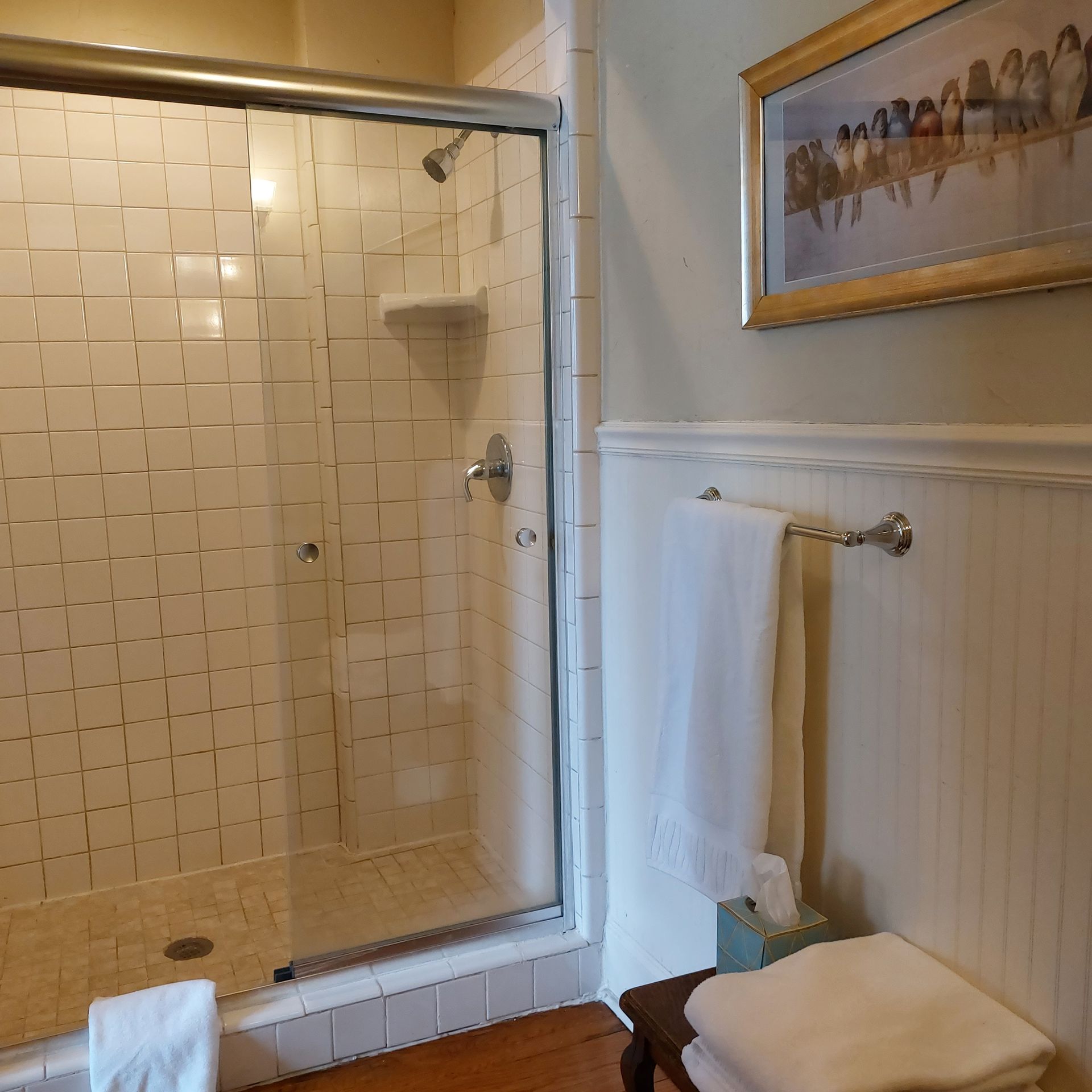 A bathroom with a picture of horses on the wall above the toilet