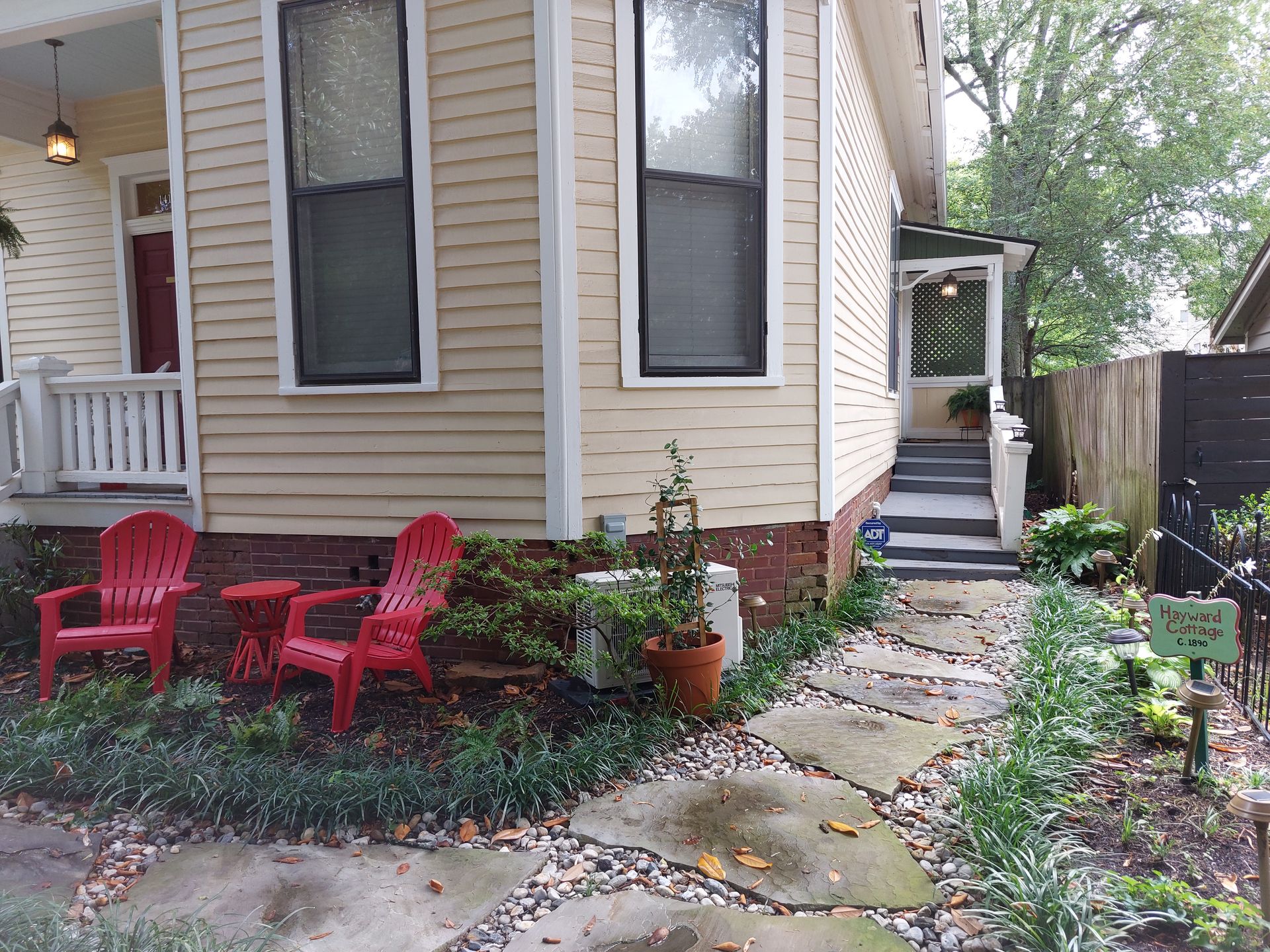 A yellow house with red chairs in front of it