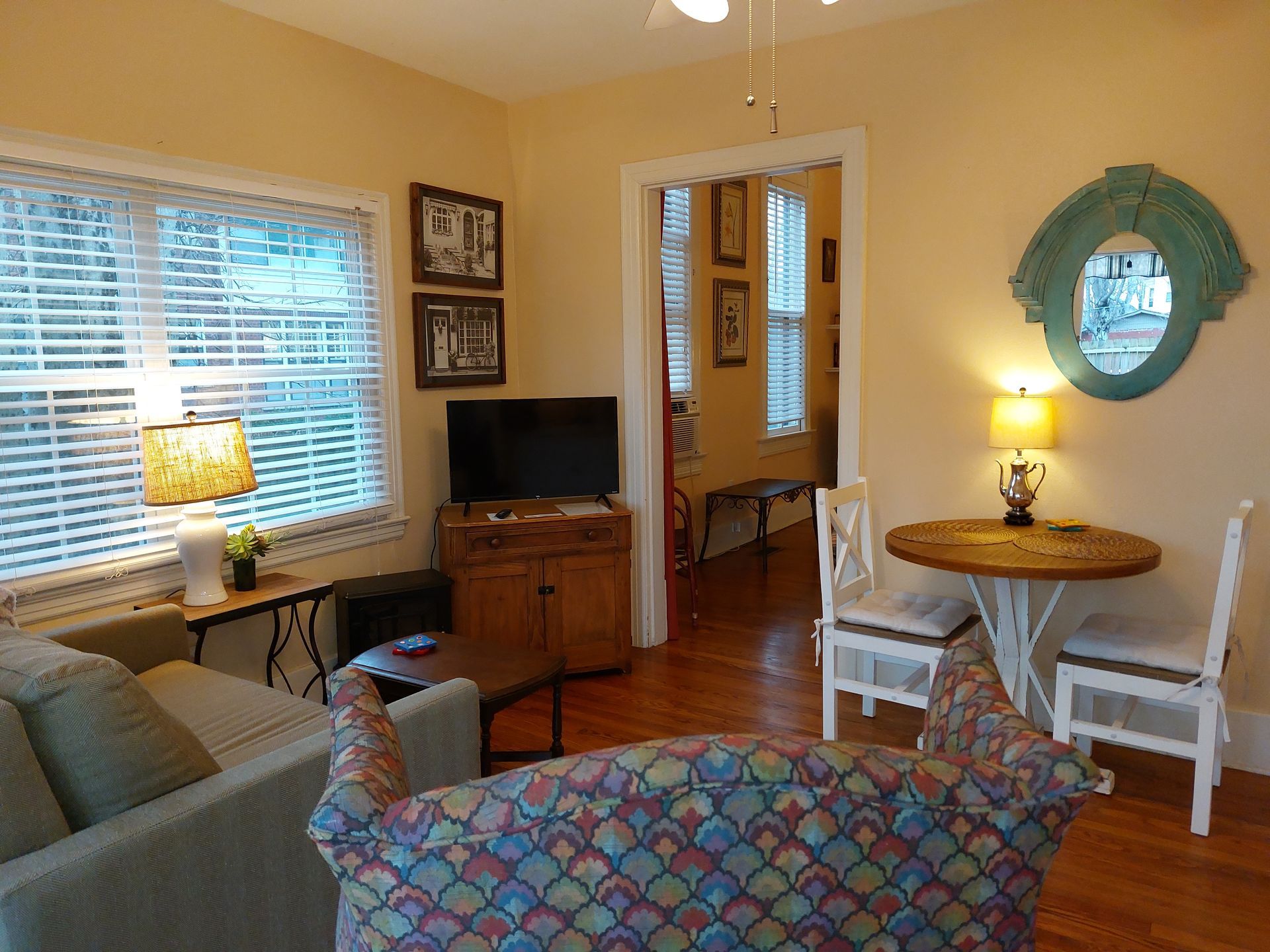 A living room with a couch , table , chairs and a flat screen tv.