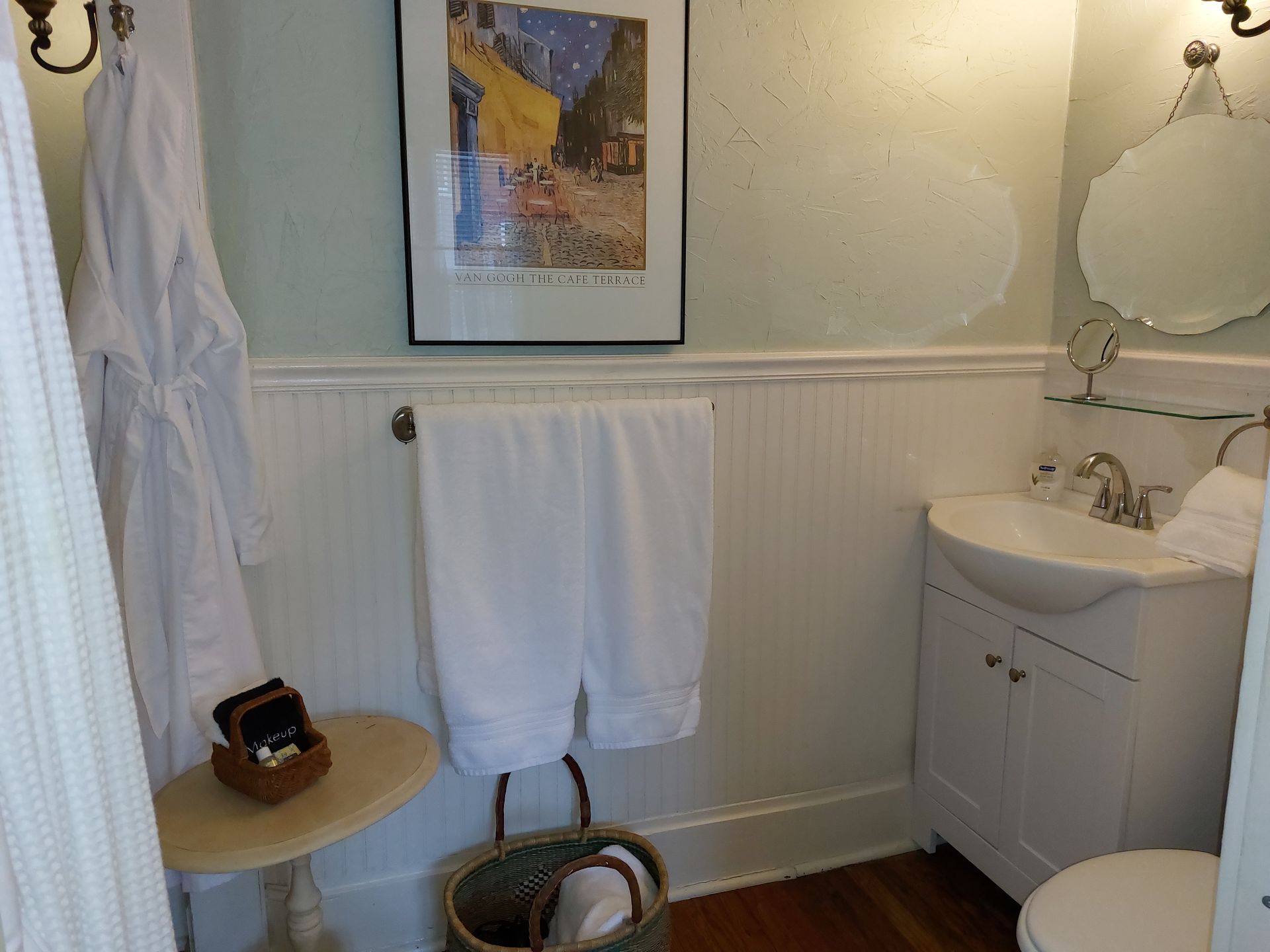 A bathroom with a sink a toilet and a picture on the wall