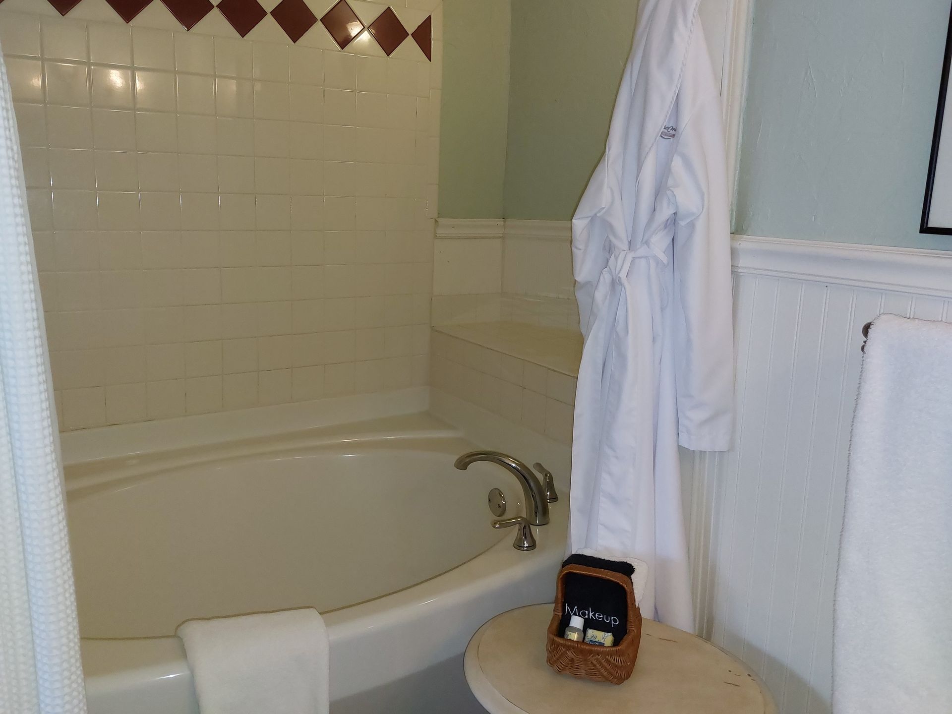 A bathtub in a bathroom with a robe hanging on the wall