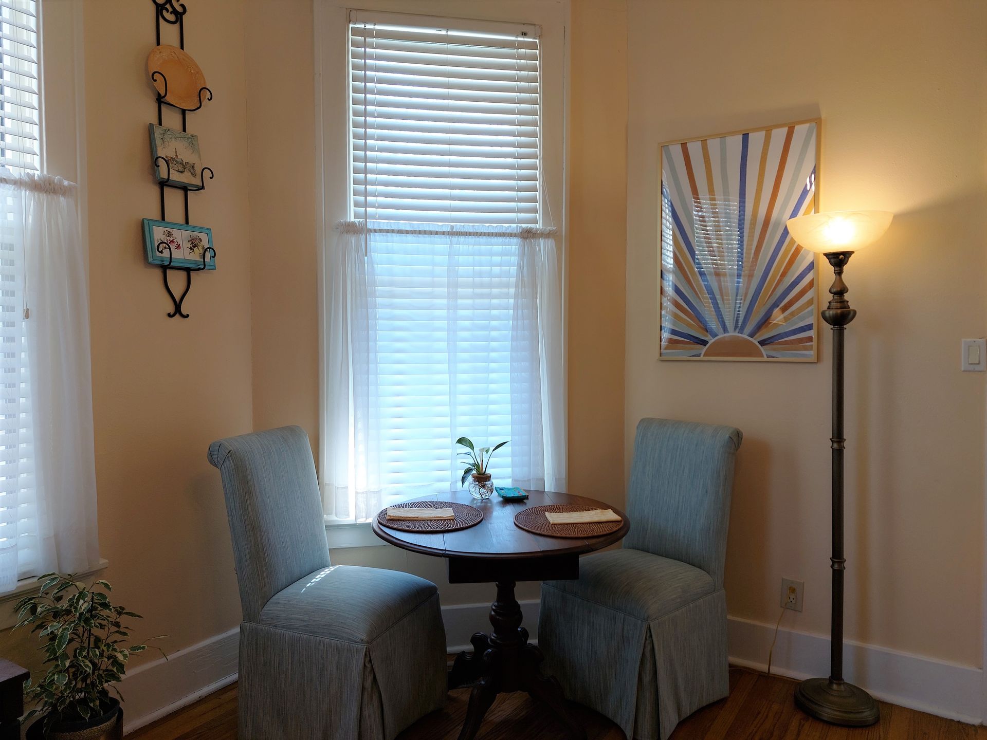 A dining room with two chairs and a table in front of a window