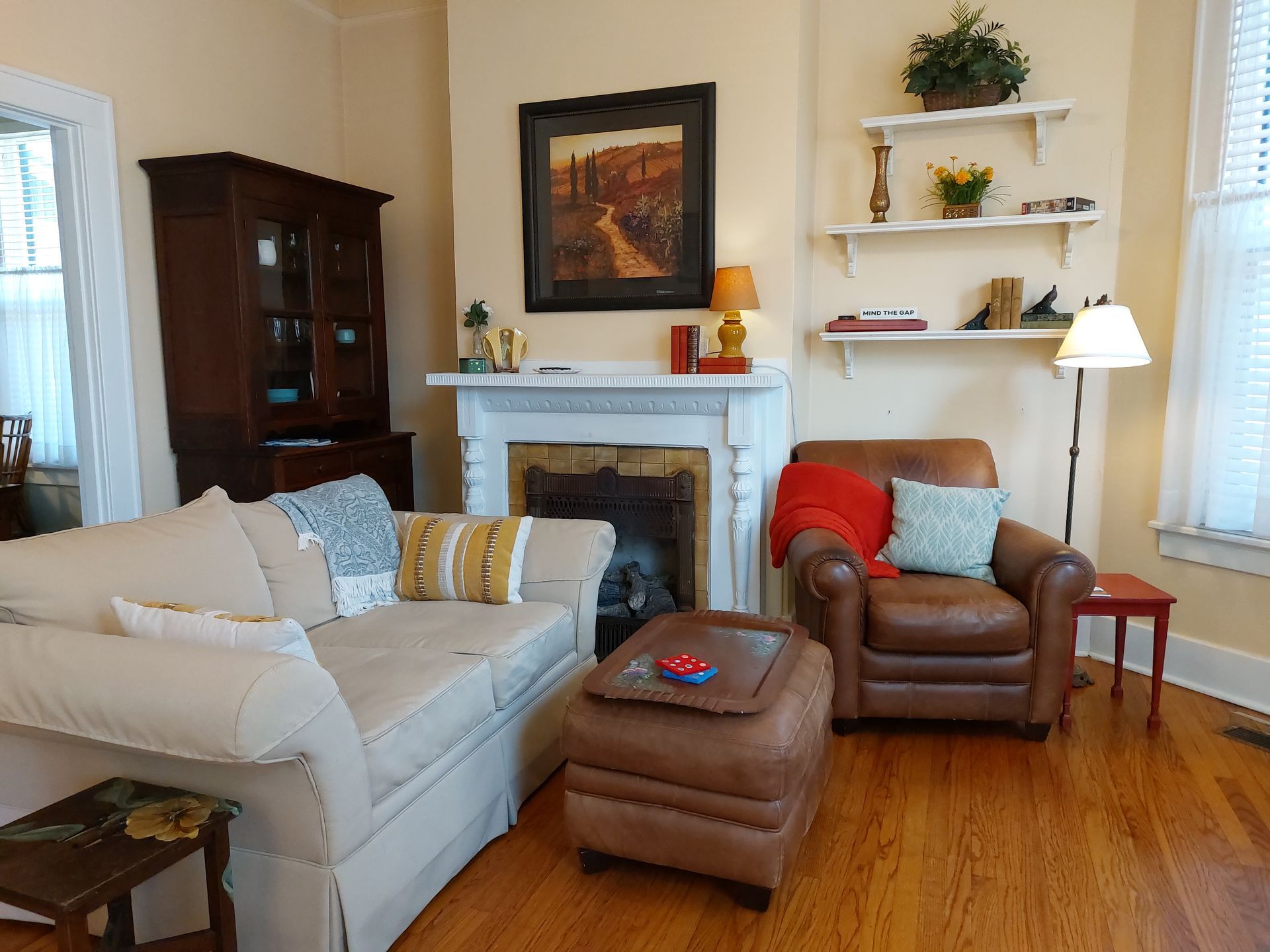 A living room with a couch , chair , ottoman and fireplace.