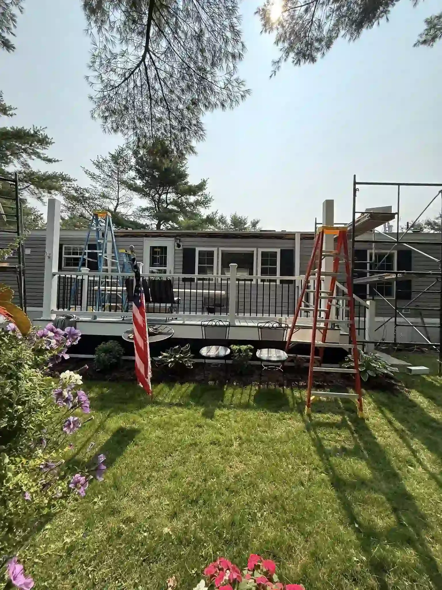 Two-car garage with tan doors, brown roof, and a driveway in front of a house against a clear blue sky.