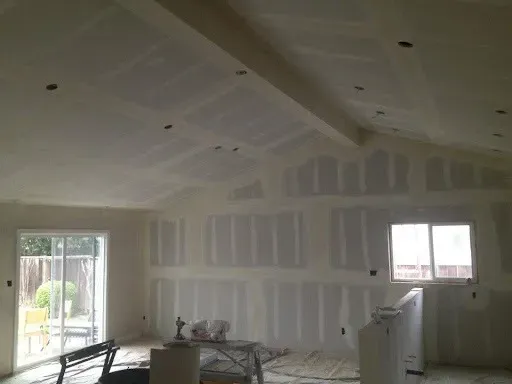 A newly poured concrete pad in a gravel area, with trees in the background under a blue sky.