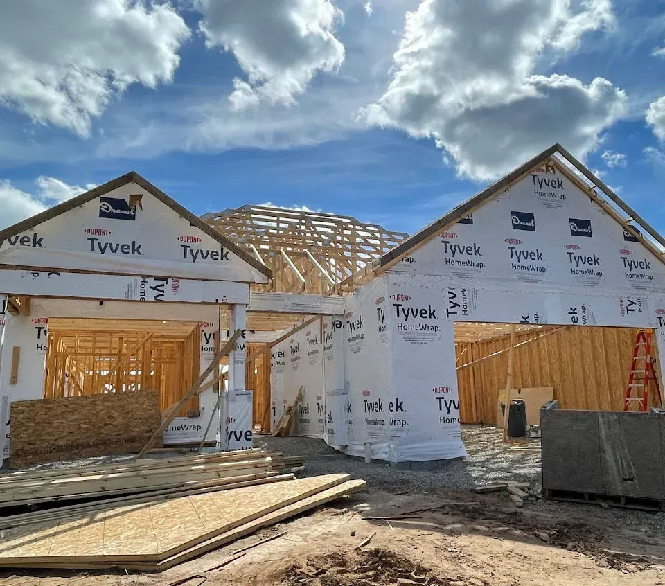 Interior of a wood-paneled cabin with a wood stove, windows, and unfinished cabinets.