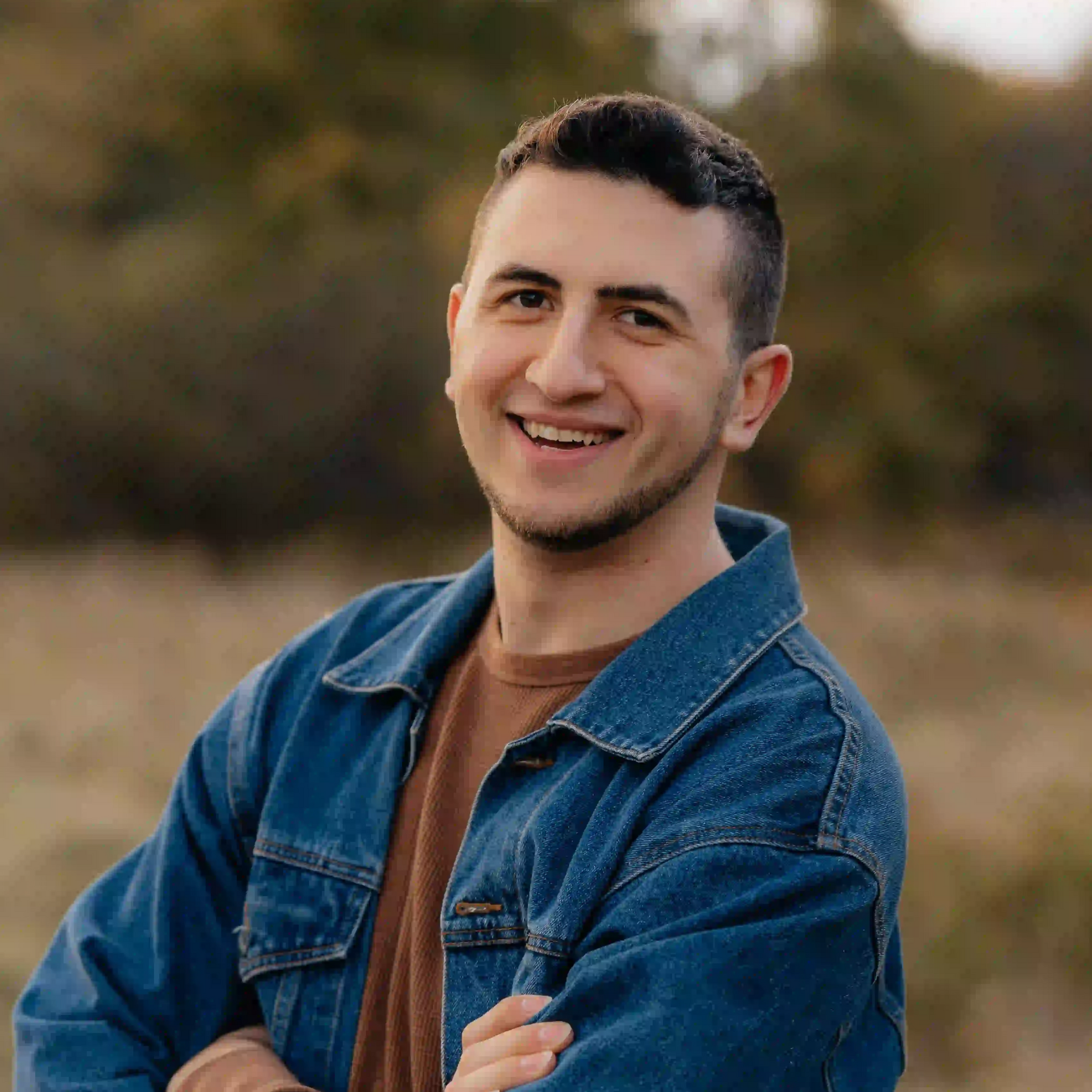 Seth Leichnitz professional headshot, smiling, wearing a brown shirt and denim jacket, outdoors.