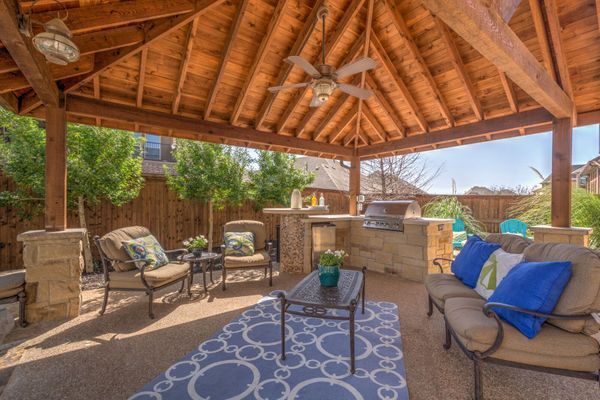 Outdoor patio with wooden gazebo, seating area, and built-in grill.