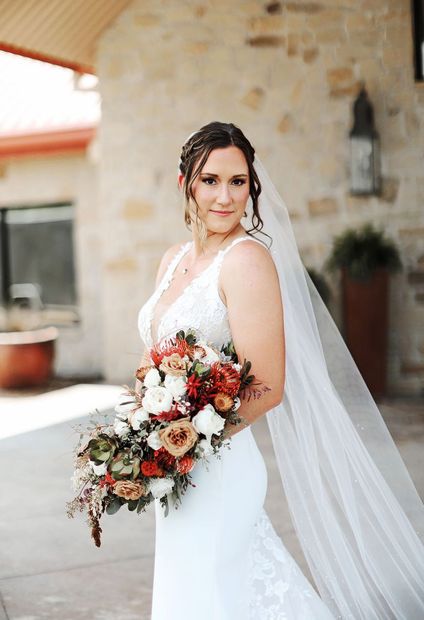 A bride in a wedding dress and veil is holding a bouquet of flowers.