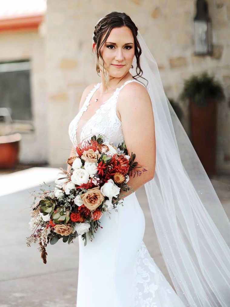 A bride in a wedding dress and veil is holding a bouquet of flowers.