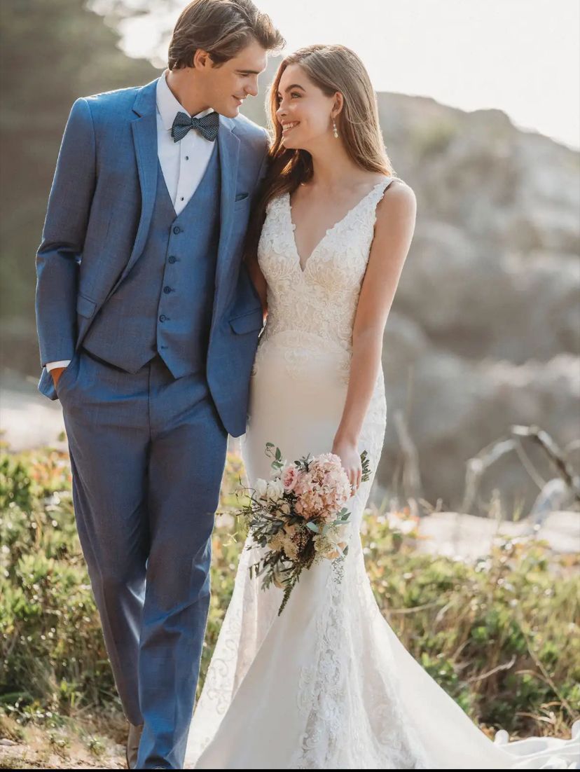 A bride and groom are standing next to each other in a field.