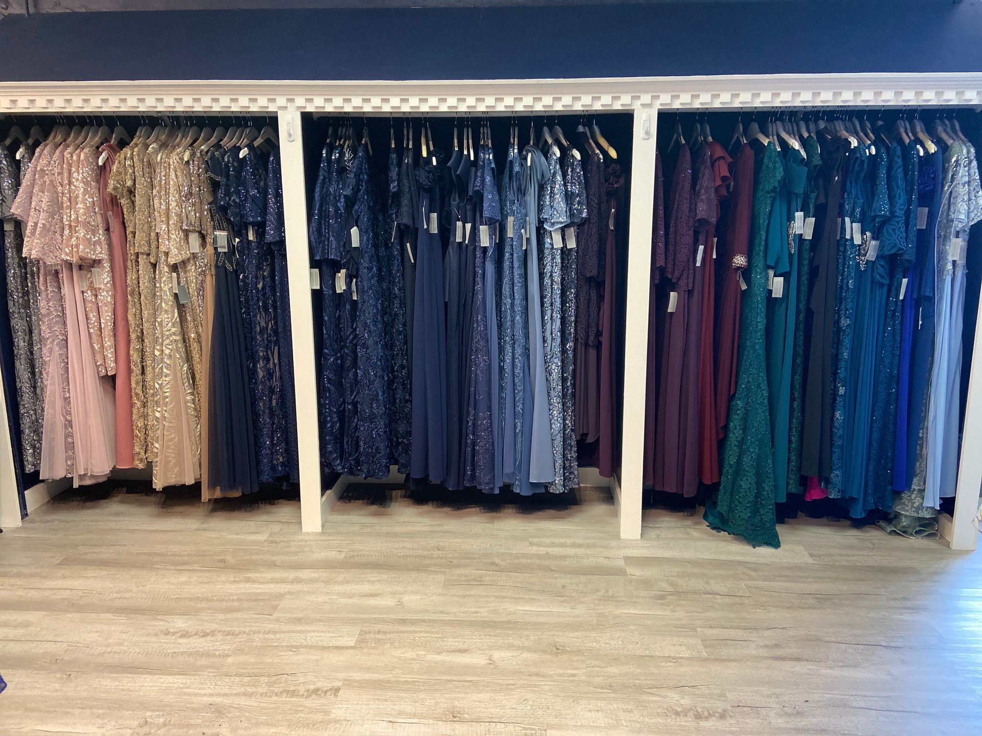 A row of dresses hanging on a rack in a store.