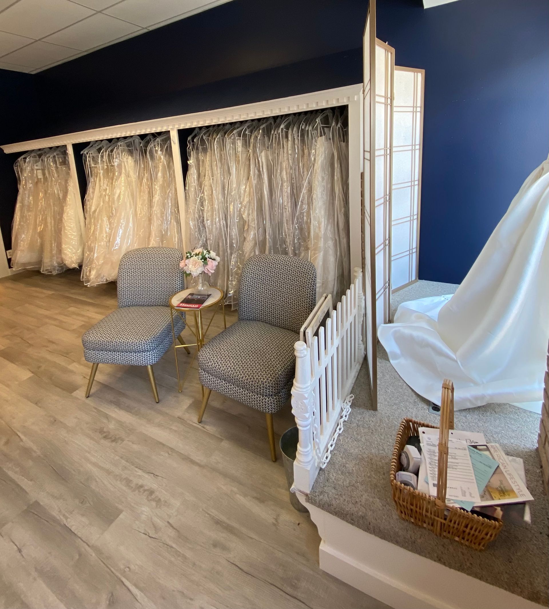 A room filled with lots of wedding dresses and two chairs.