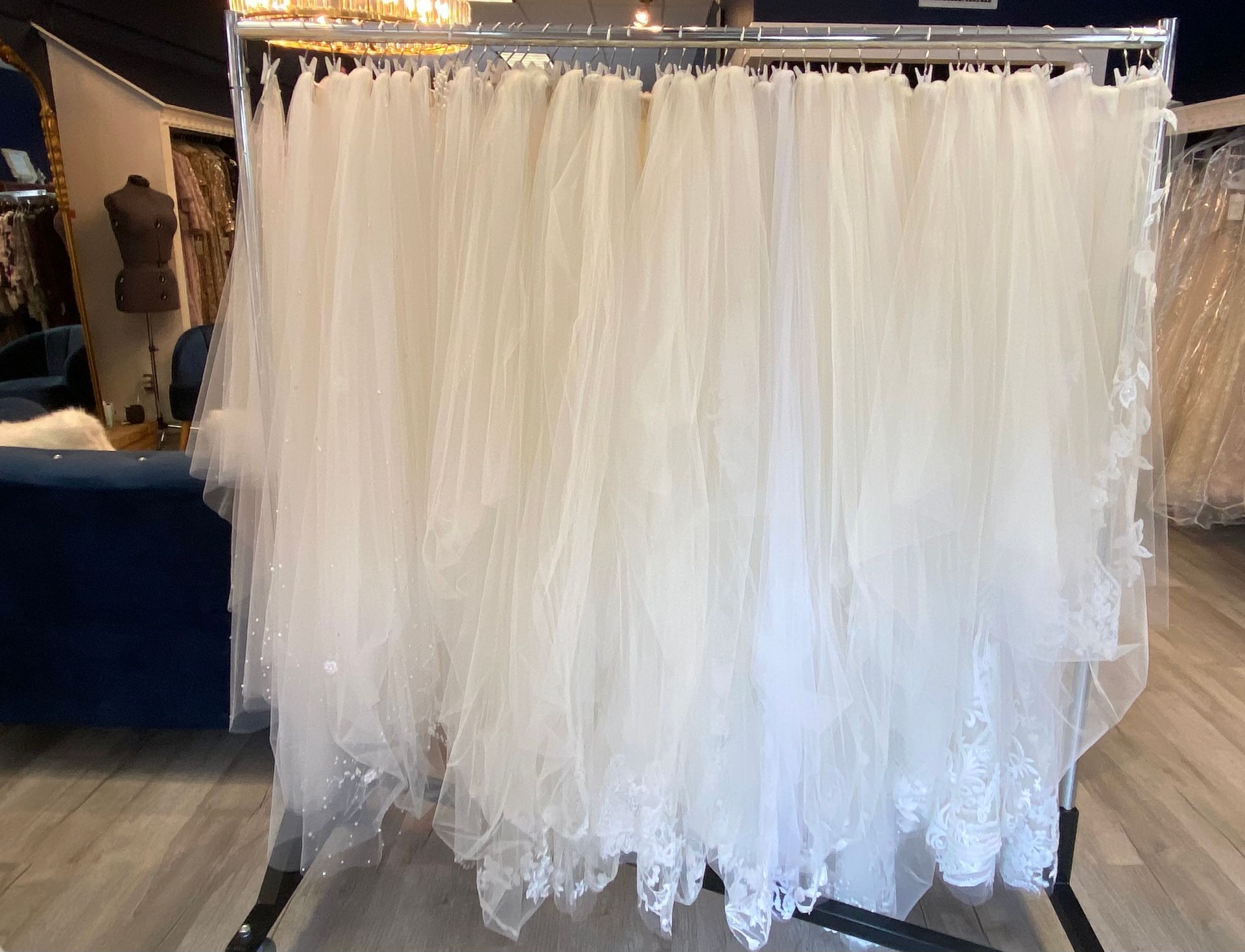 A bunch of white dresses are hanging on a rack in a store.