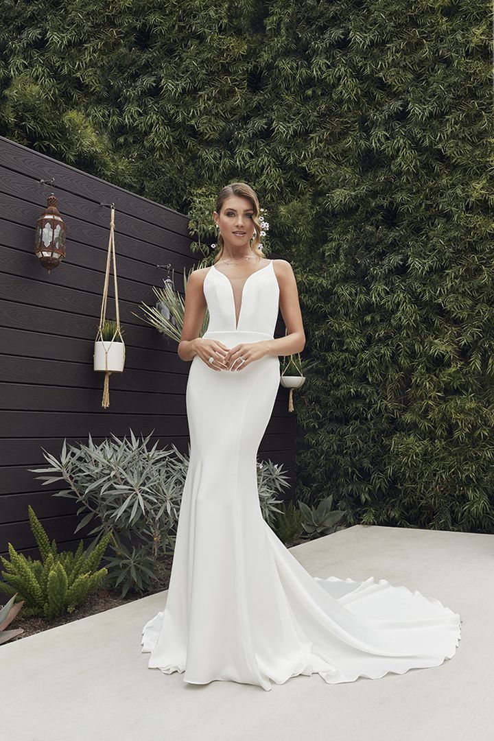 A woman is wearing a white wedding dress with a plunging neckline.