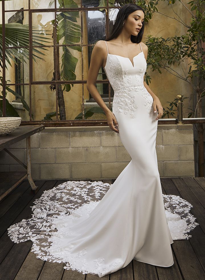 A plus size model is wearing a strapless wedding dress with a high slit.