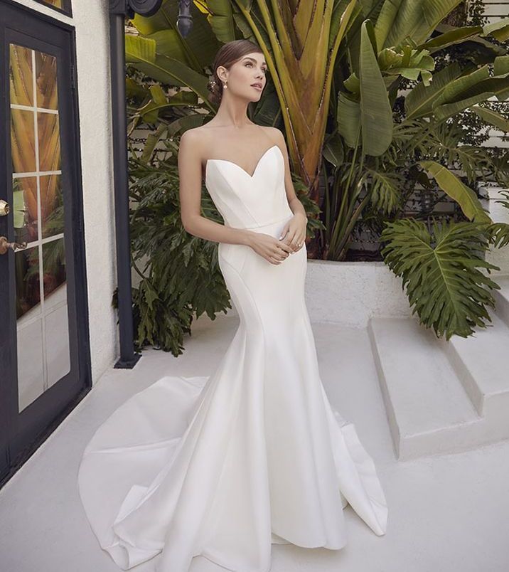 A woman is wearing a white wedding dress with long sleeves.