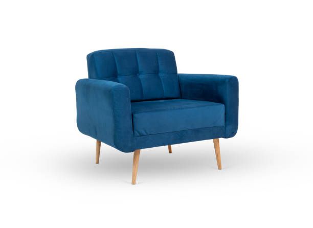 A deep blue, velvet-upholstered armchair with a tufted backrest and light wooden tapered legs, isolated on white.