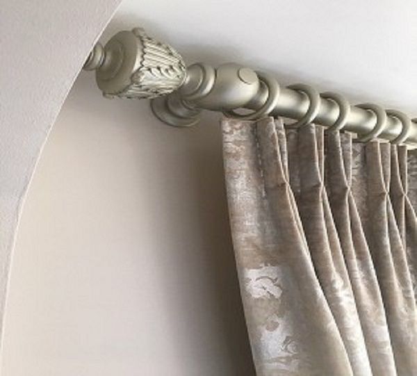 Curtains with a pinch pleat heading tape on a metal pole with decorative finial ends