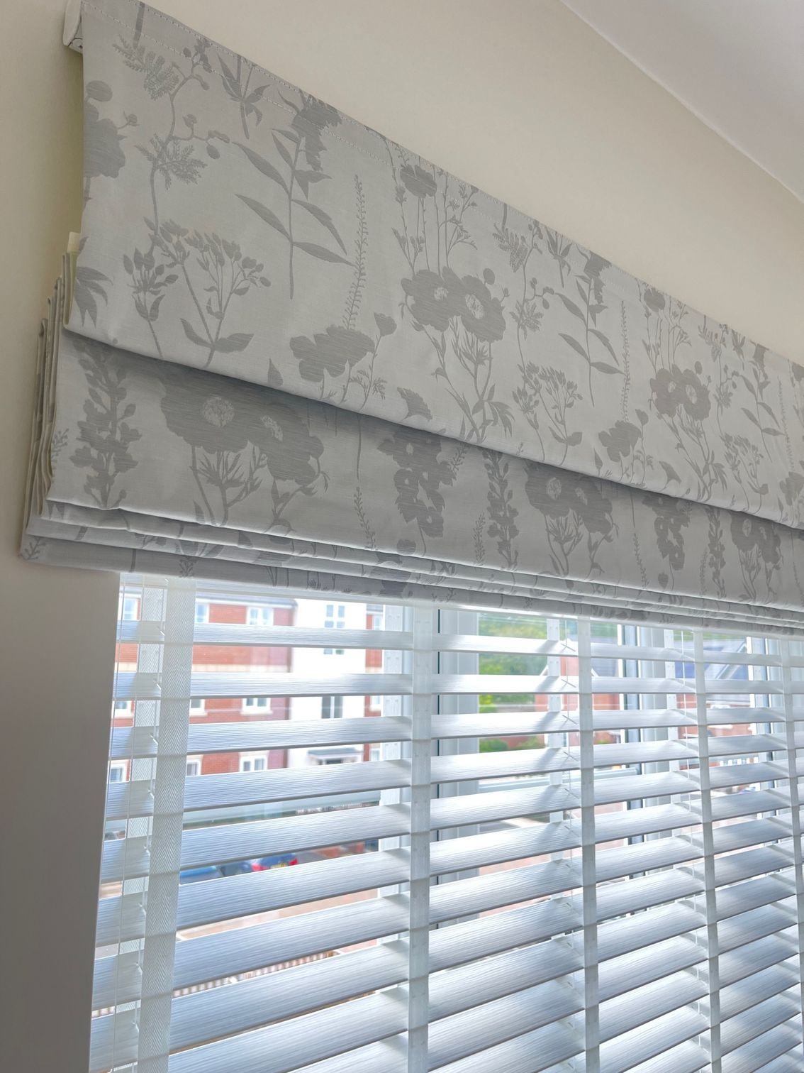 A close up of a white wooden blind on a window.
