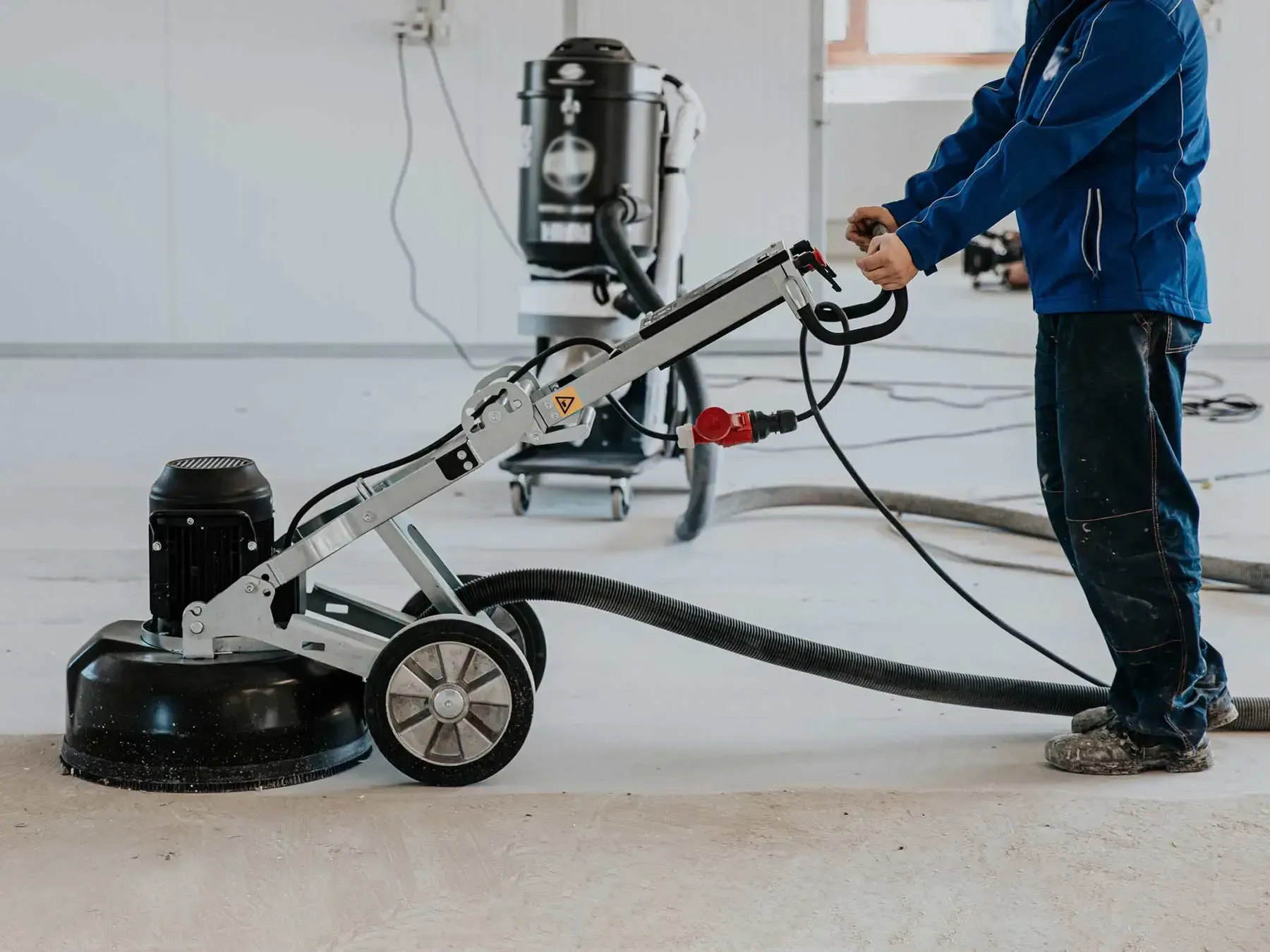 A man is using a grinder on a concrete floor.