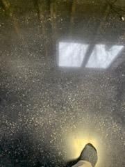 A person is standing on a wet floor with a light shining on it.