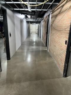 A long hallway in a building with brick walls and a concrete floor.
