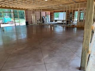 A large room with a concrete floor and wooden pillars.