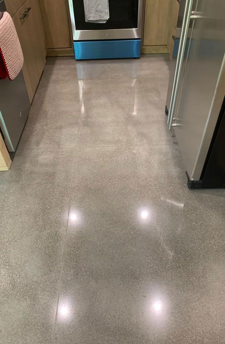 A kitchen with a shiny concrete floor and stainless steel appliances.