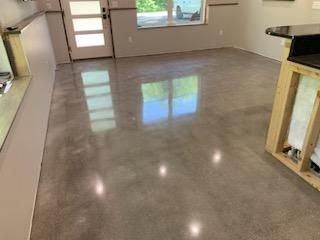 A living room with a shiny concrete floor and a window.