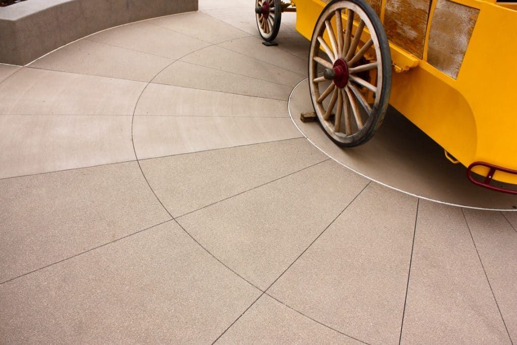 A yellow horse drawn carriage is parked on the sidewalk