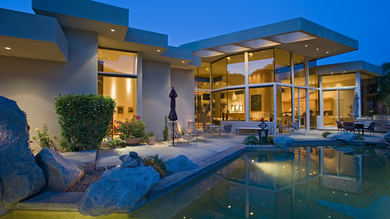 A modern house with a large swimming pool in front of it.
