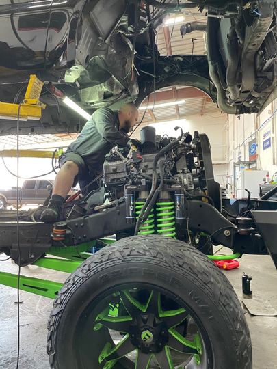 Lifted Green Suspension Truck Under Repair | Full-Service Auto Repair